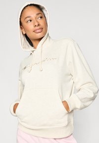 Φούτερ με κουκούλα σε μπεζ χρώμα, κατασκευασμένο από μαλακό ύφασμα, με μπροστινή τσέπη, κουκούλα με κορδόνι και χρυσαφί λογότυπο "Champion".