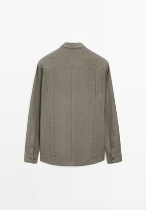 Szara lniana koszula z długim rękawem, zapinanymi na guziki mankietami, widocznymi pionowymi szwami na plecach i małym kołnierzykiem.