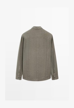 Langärmliges graues Leinenhemd mit geknöpften Manschetten, sichtbaren vertikalen Nähten am Rücken und kleinem Kragen.