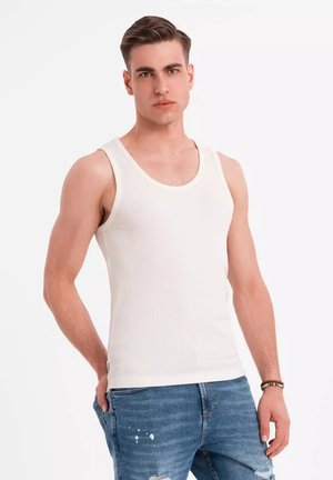Weißes, geripptes Tanktop mit Rundhalsausschnitt, ausgestattet mit schmalen Trägern, kombiniert mit ausgebleichten blauen Jeans.