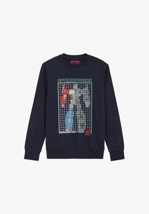 Sudadera azul marino con gráfico de Optimus Prime, mitad coloreado y mitad en alambre, de pie frente a un fondo cuadriculado y texto "OPTIMUS PRIME" arriba.