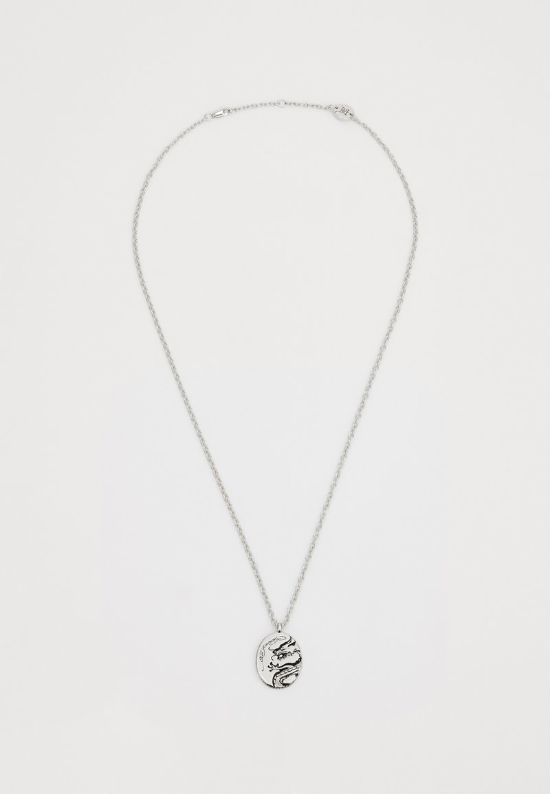 Srebrna verižica z ovalnim obeskom, ki ima črn vzorec z zmajem in zapletenim okrasjem. Veriga ima teksturiran zaključek.