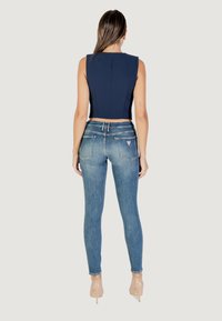 Haut court marine avec un design structuré, associé à un jean skinny bleu délavé avec un style classique à cinq poches et un détail de logo.