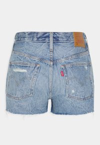 Světlemodré džínové kraťasy s ohrnutým lemem, dvěma zadními kapsami s prošíváním a hnědou koženou nášivkou na pase.