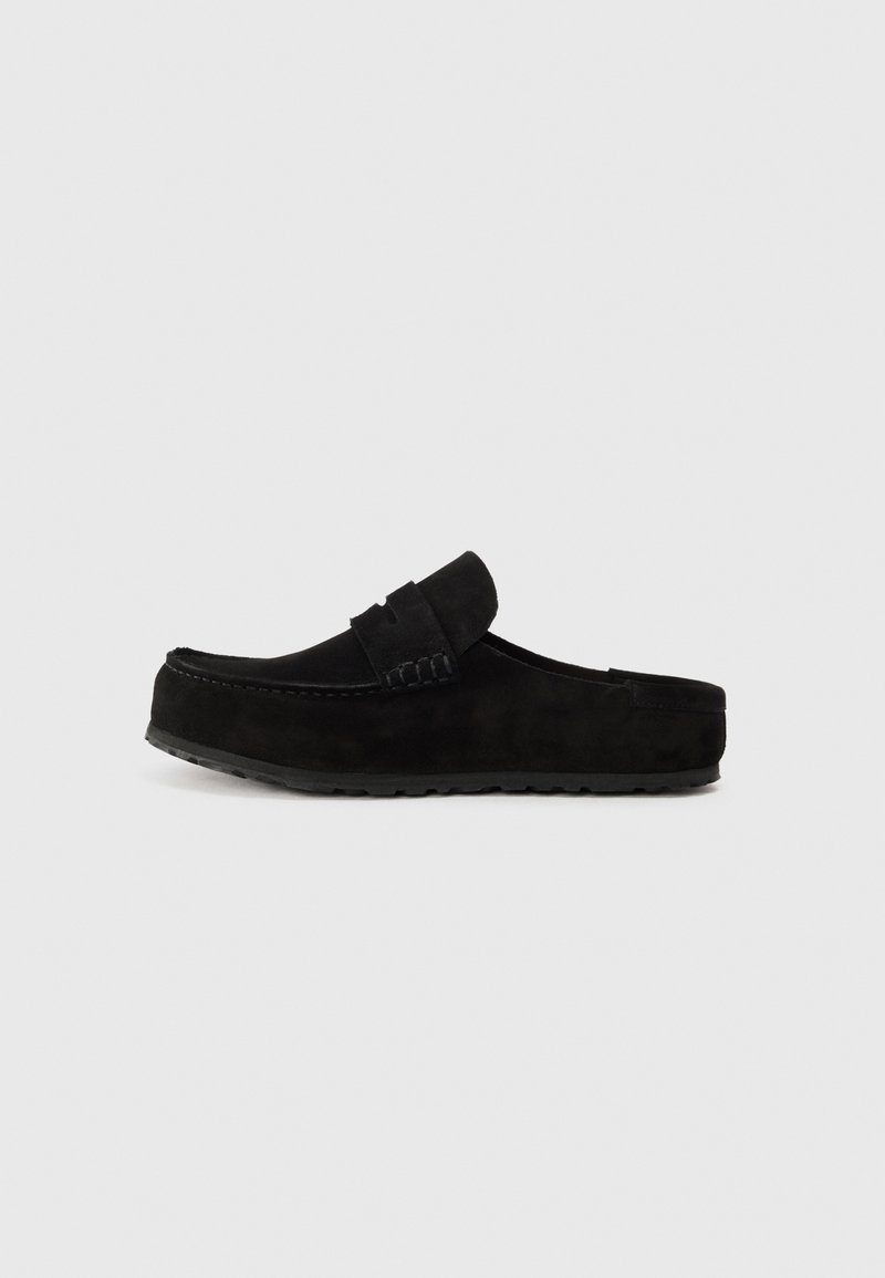 Sorte suedes slip-on sko med rund tå, en dekorativ stropp over oversiden, og en teksturert gummisåle.