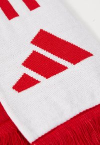 Red and white knitted scarf featuring a geometric design with three red triangular shapes, finished with fringe edges.