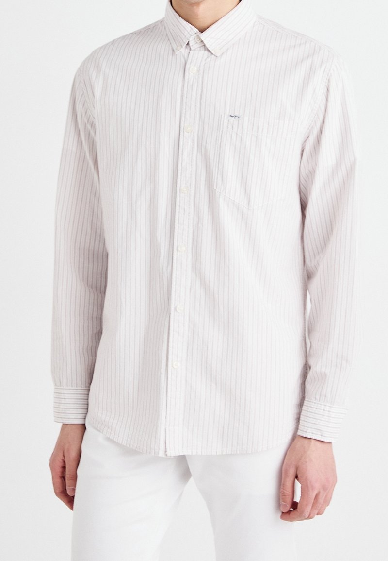 Koszula z guzikami w jasnym kremowym kolorze z cienkimi pionowymi różowymi paskami. Posiada klasyczny kołnierz, długie rękawy oraz kieszonkę na piersi.
