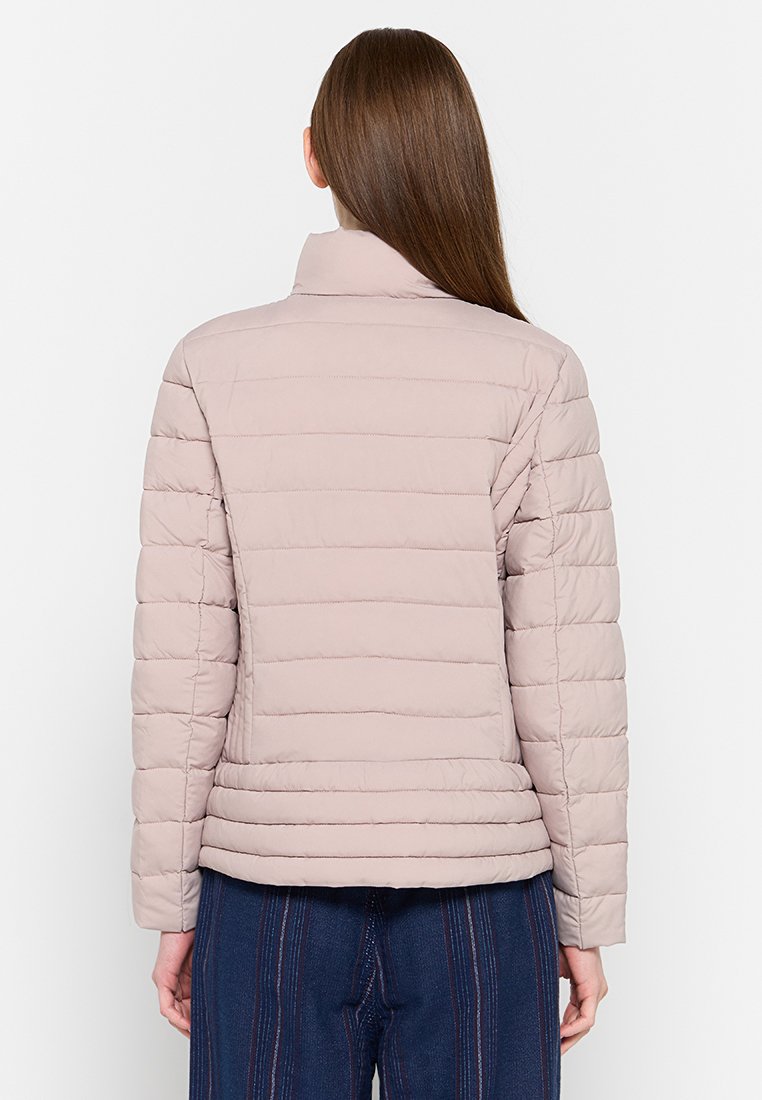 Giacca imbottita in beige chiaro con colletto alto. Caratterizzata da trapuntature orizzontali, maniche lunghe e una silhouette aderente. Texture morbida.