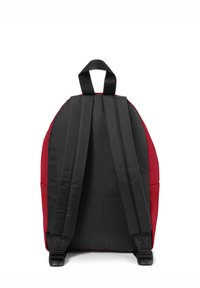 Mochila negra y roja con forma redondeada, que cuenta con correas de hombro acolchadas, un asa superior y una textura de tela suave.