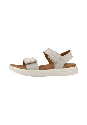 Beige offene Sandale mit verstellbaren Klettverschlüssen und weißer, gepolsterter Sohle, entworfen für den Freizeitgebrauch und Komfort.