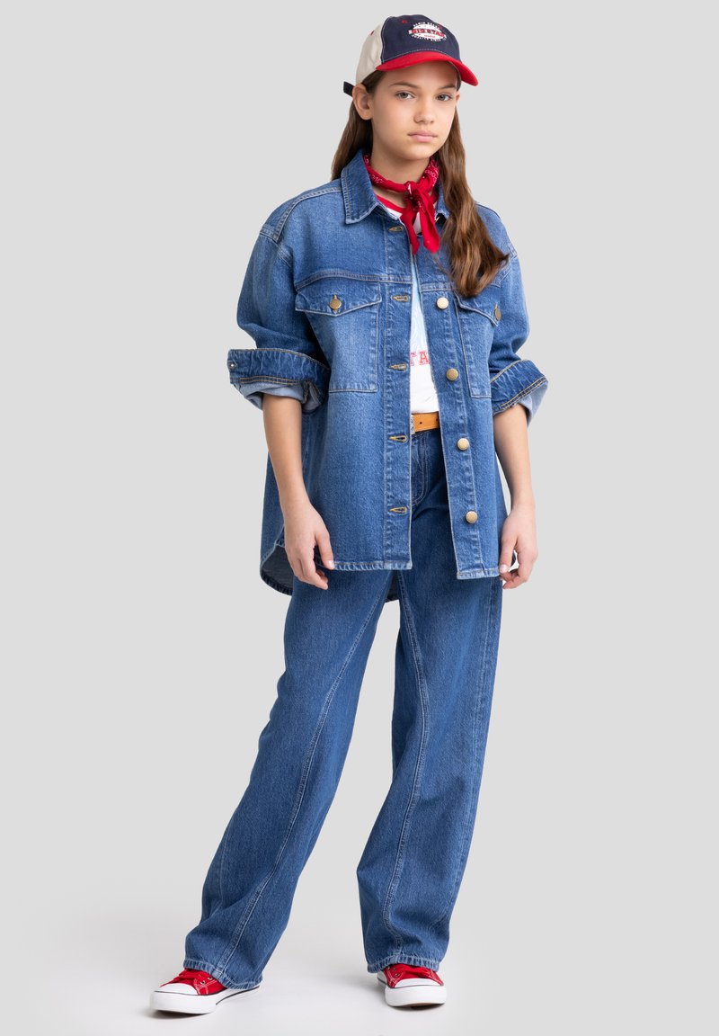 Denim jacket suurte ees taskutega, sinised teksad, punased tennised ja punane bandaan. Valge graafikaga t-särk jakki alla, punase ja sinise kübara tal.