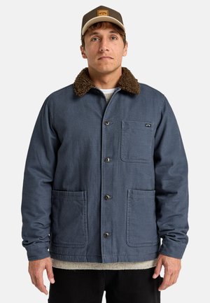 Navy blue work jacket with a brown fur collar, two front pockets, front button closures, and medium-weight fabric.