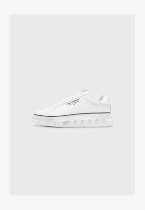 Zapatilla blanca de corte bajo con suela gruesa transparente y texto negro "Karl Lagerfeld" en el lateral sobre un fondo liso.