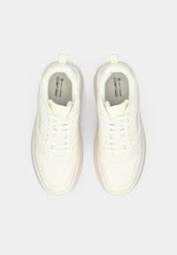 Balti veganiški sportbačiai su glotniu, tekstūruotu paviršiumi, apvaliu priekumi, paminkštintu apykakle ir tradiciniais raišteliais. Matomi subtilūs dizaino akcentai ir logotipas.