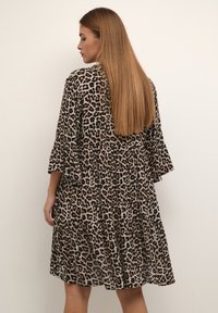 Klänning i leopardmönster med ett lagerdesign, som har volangärmar i tre fjärdedelar och ett mjukt, lätt tyg. Bruna och beige färgtoner.