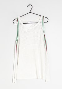 Witte mouwloze gebreide top met groene en rode afwerking op de armsgaten, hangend aan een zwarte hanger tegen een witte achtergrond.