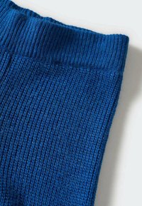 Blauwe gebreide stof met een geribbeld patroon. De stof heeft verticale lijnen en een zachte, rekbare afwerking langs de bovenrand.