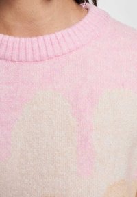 Myk, strikket genser med en ribbet rosa krage. Har et gradientdesign i lyse rosa og beige toner, som viser en glatt tekstur.