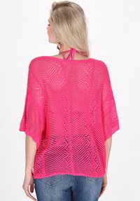 Rosa gestricktes Top mit lockerer Passform, kurzen Ärmeln und einer Schleife am Hals, präsentiert vor einem hellen Hintergrund.