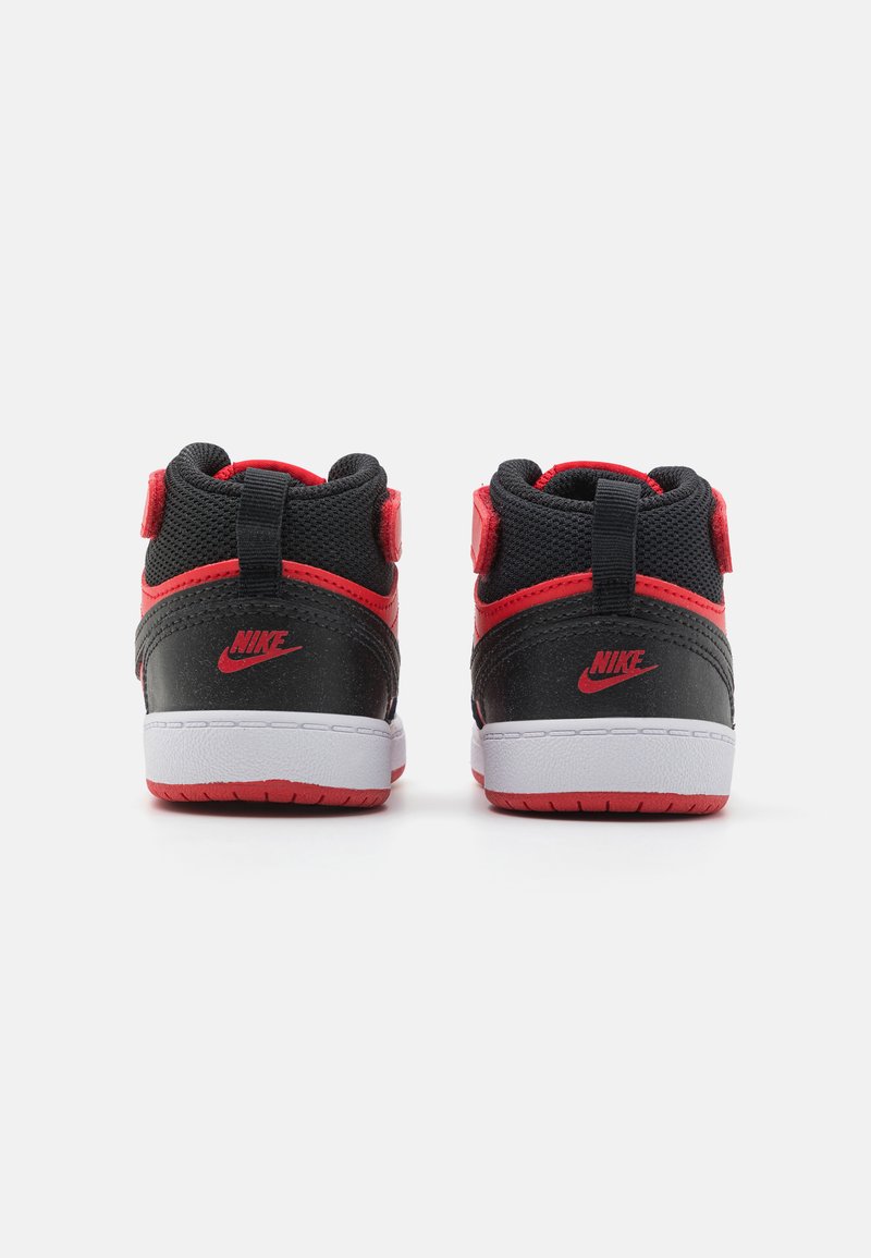 Zapatillas altas en negro y rojo con parte superior de malla texturizada, collar acolchado y suela de goma blanca, con un destacado logo de Nike en el talón.