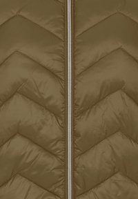 Alyvuogių žalios spalvos pūstas paltas su chevron formos siuvinėtu raštu, sidabriniu centrinio užtrauktuko ir lygiu nailono paviršiumi.