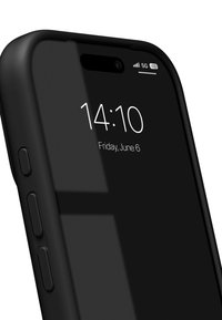 Musta älypuhelin, jossa lasinen etupinta, näyttäen ajan ja päivämäärän. Sivupainikkeet näkyvissä. 5G-ilmaisin oikeassa yläkulmassa. Sileä pinta.