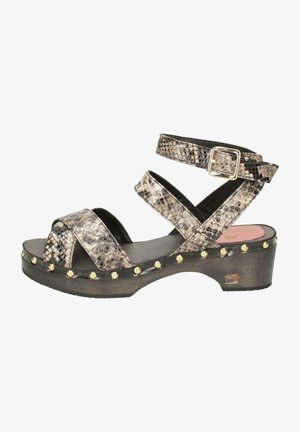 Clogs with a wood base, featuring a beige and black snake print upper, multiple crossover straps, gold-tone studs, and a buckle closure.