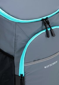 Sac à dos gris avec des fermetures éclair turquoise, doté de deux poches extérieures et d'une texture lisse. Comprend une poche latérale en filet noir et un détail de logo.