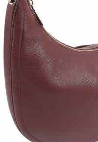 Bordeaux leren schoudertas met een ronde vorm, gestructureerd oppervlak, gouden ritsdetails en stiksels langs de zijkanten.