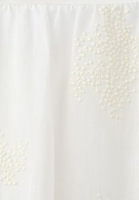 Biała tkanina z delikatnym, fakturowanym haftem kwiatowym oraz marszczeniem wzdłuż górnej krawędzi.