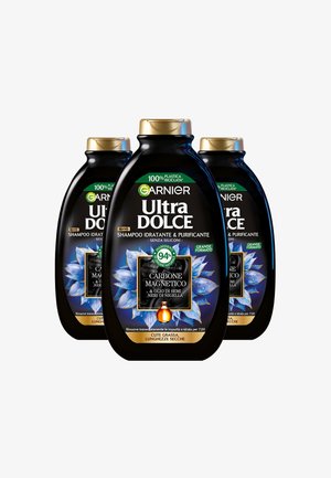 Tre bottiglie di shampoo nere con tappi dorati. Le etichette mostrano "Garnier Ultra Dolce", indicando carbone attivo e olio di semi di nigella.