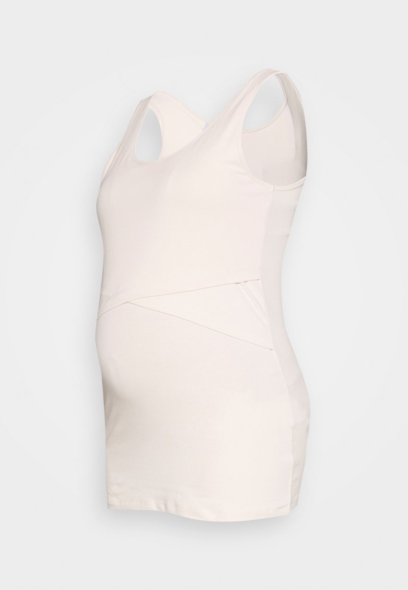 Top de maternidade em tecido leve e suave em bege claro. Apresenta um design cruzado e material elástico para conforto à volta da barriga.