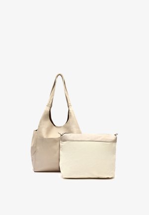 Bolso tote de cuero beige con correas anchas para el hombro junto con una bolsa beige a juego con cremallera. Ambos bolsos tienen superficies lisas y lisas.