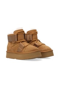 Bruine suède enkelboots met een zachte voering, voorzien van verstelbare bandjes, een stevige zool en textuuraccenten.