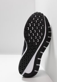 Suola di scarpa atletica nera con un battistrada a motivo esagonale, caratterizzata da accenti bianchi e una superficie testurizzata per presa e flessibilità.