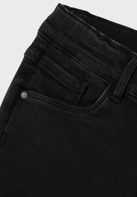 Jeans de mezclilla negros con cintura alta, bolsillo frontal con detalle de botón y costuras visibles en los bordes. La textura parece suave.