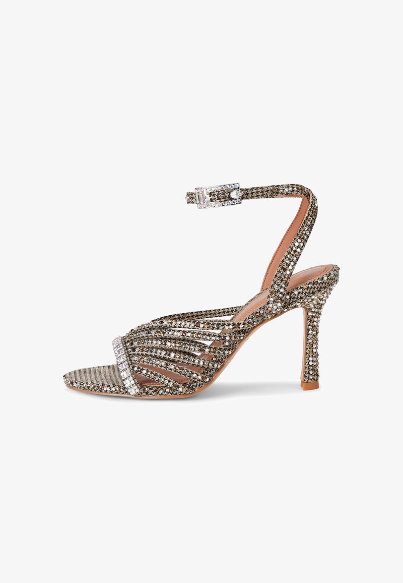 High-heeled sandal with thin sparkling straps, an ankle strap with a rhinestone buckle, and a textured sole in neutral tones.