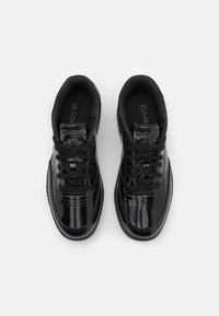 Un paio di sneaker Reebok Classic nere e lucide con lacci neri, viste dall'alto su uno sfondo bianco.