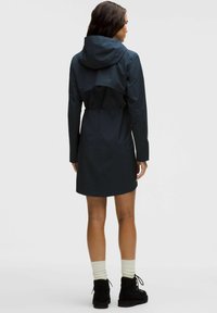 Palton impermeabil de un albastru închis, cu talie strânsă, glugă și mâneci lungi; are un design elegant și o textură fină.