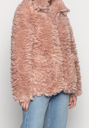 Zachte, donzige, stoffige roze faux fur jas met rits, gedragen over lichtblauwe spijkerbroek, met zichtbare halslijn tot heupen en een ontspannen pasvorm.