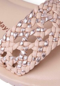 Lanière de sandale tressée composée de bandes de cuir beige mat et or rose métallique entrelacées sur une semelle nude.