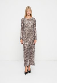 Langarm maxi kjole med leopardmønster, laget av skinnende stoff. Har en rett silhuett og rund hals. svarte høye hæler.