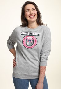 Felpa grigia in cotone con un design pixelato colorato di Minecraft, raffigurante un axolotl in un bicchiere. Maniche e vita a costine.