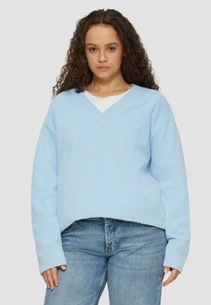 Lichtblauwe, oversized v-hals trui gemaakt van zachte stof; heeft lange mouwen en ribbelstructuur langs de halslijn. Gecombineerd met denim jeans.