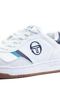 Fehér bőr sneaker kék akcentusokkal, szürke csíkkal és hímzett logóval. Kerek fűzőkkel és gumi talppal rendelkezik.