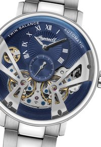 Automatische horloge met een blauwe textuur dial, zilveren kast en transparante achterkant. Heeft gouden accenten en blootgestelde binnenmechanismen.