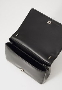 Black leather handbag with a smooth texture, rectangular shape, and a silver clasp. Interior features two main compartments and metal accents.