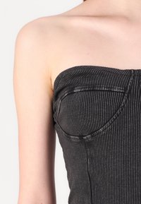 Must mustriba TOP, millel on sooniline tekstuur, sobib kehakujule ja väärindatud õmblustega kaeluses ja külgedel.