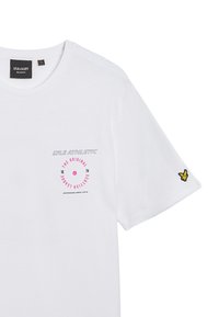 Hvit bomull t-skjorte med et sirkulært rosa grafisk design på brystet, med teksten "Lyle Athletic", og en gul brodert logo på ermet.