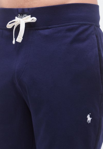 Αθλητικό σορτς σε ναυτικό μπλε χρώμα με κορδόνι στη μέση, λευκό λογότυπο ως διακοσμητικό και απαλό βαμβακερό ύφασμα. Λείο υλικό, άνετη εφαρμογή.